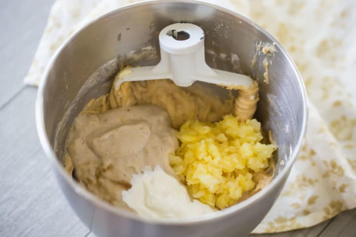 Mixing bowl with hummingbird cake batter, bananas, pineapple, and sour cream.
