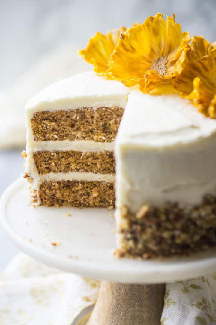 Close-up of southern hummingbird cake with cream cheese frosting, pecans, and pineapple flowers.