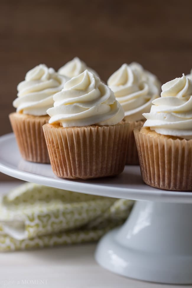 Vanilla cupcakes with a tall swirl of frosting, arranged on a cake stand.