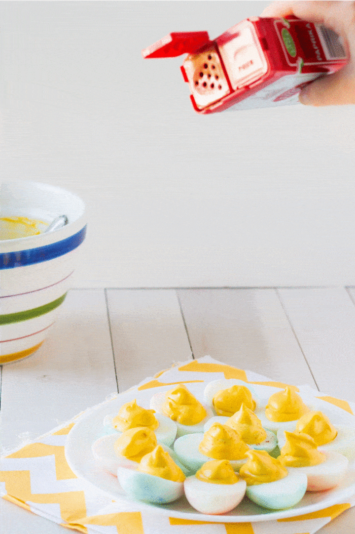 Animated gif of deviled eggs being sprinkled with paprika.