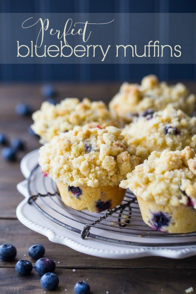 Vertical Image of bakery-style blueberry muffins on a cooling rack with text overlay.