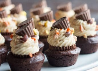 Outrageous! These brownie bites were so fudge-y and chocolate-y, and loaded with Reese's! A miniature peanut butter cup is tucked inside, then it's topped with no-bake peanut butter cheesecake, chopped Reese's Pieces, and and Reese's mini on top! #snacktalk #ad