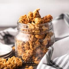 Peanut butter granola in a glass jar with a plaid cloth.