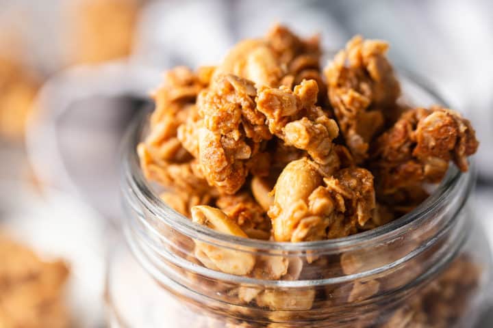 Granola with peanut butter, piled into a jar and spilling over the rim.