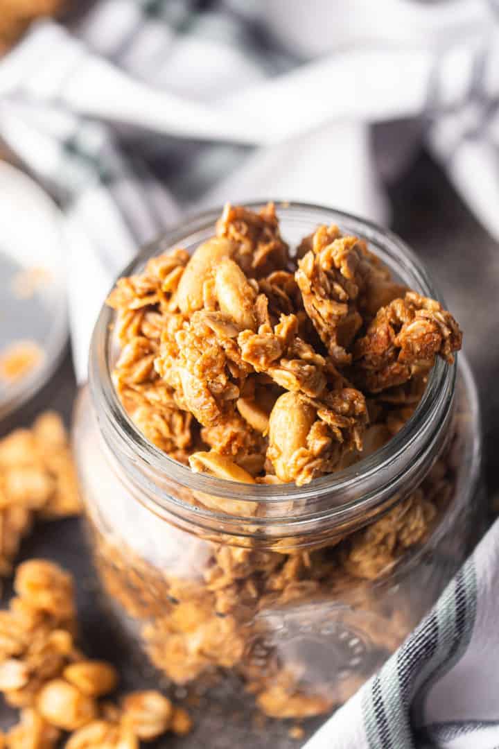 Peanut butter granola recipe, broken into clusters and placed in a glass jar.