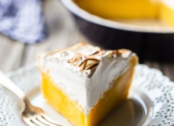 Lemon meringue pie on a lacy white plate.