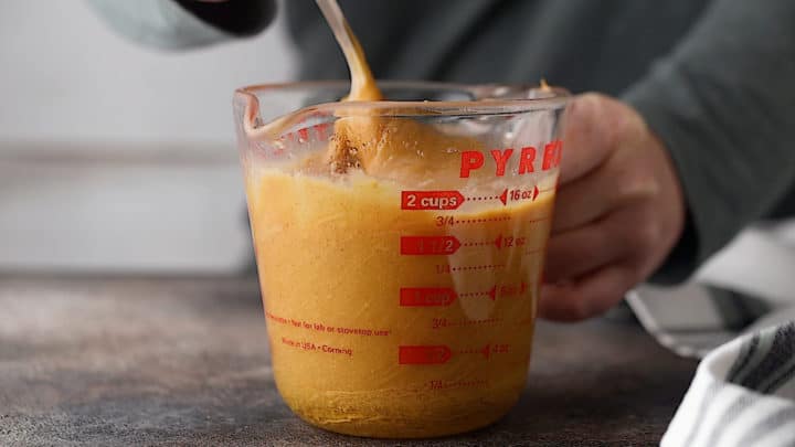 Stirring the liquid ingredients together in a large liquid measuring cup.