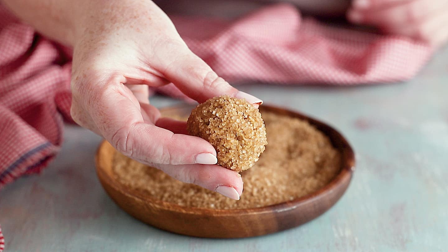 Rolling ginger cookies in coarse sugar.