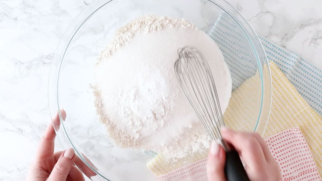 Whisking dry ingredients together in a large mixing bowl.