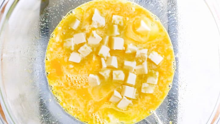 Adding cubed butter to a homemade lemon curd recipe.
