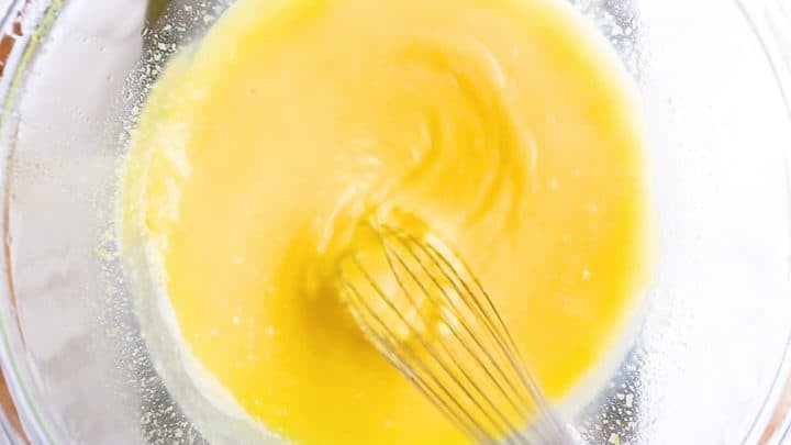 Whisking lemon curd over a double boiler until the whisk leaves tracks and the mixture is thickened.