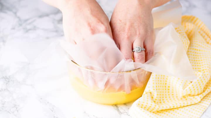 Pressing plastic wrap directly onto the surface of the hot lemon curd.