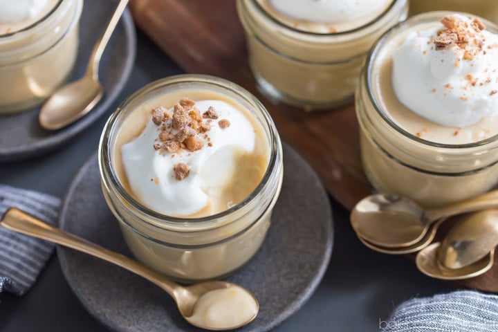 Butterscotch pudding in a jar with a spoonful taken out, showcasing the creamy texture of the dessert.