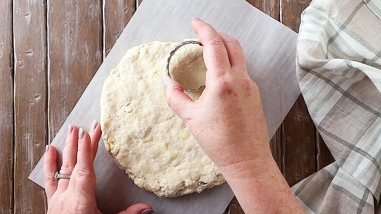 Cutting homemade buttermilk biscuit dough with a 2-inch diameter cutter.
