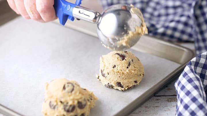 Scooping cookie dough onto a sheet pan before baking.