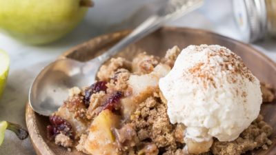 Pear cranberry crisp: a comforting cool-weather dessert! Sweetened with maple syrup, spiked with warm ginger, and topped with a buttery oatmeal pecan crumb.