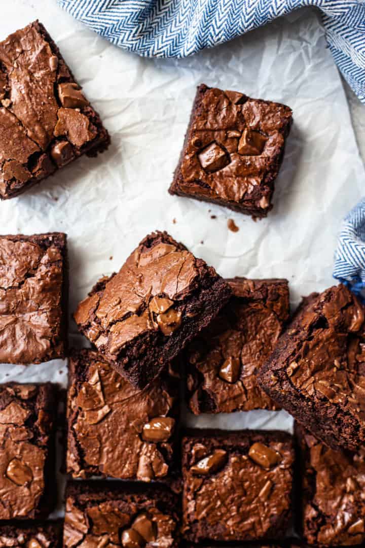 Best brownie recipe, prepared and cut into squares on a white background with a blue cloth.