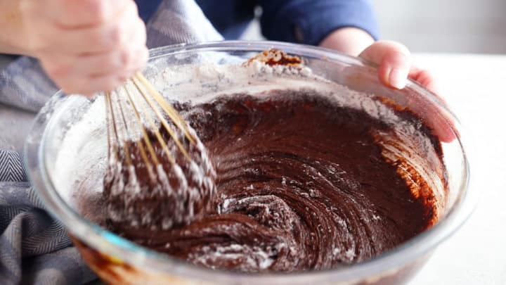 Adding dry ingredients to a brownie recipe.
