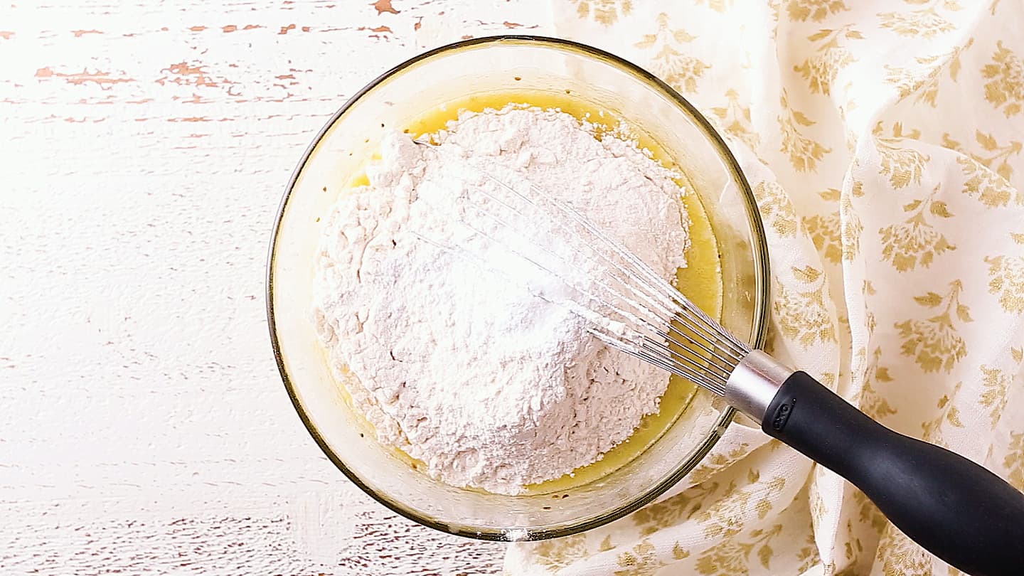 Adding flour, baking powder, and salt to pizzelle batter.