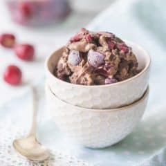 A bowl of chocolate ice cream, studded with dark sweet cherries and chocolate chunks.