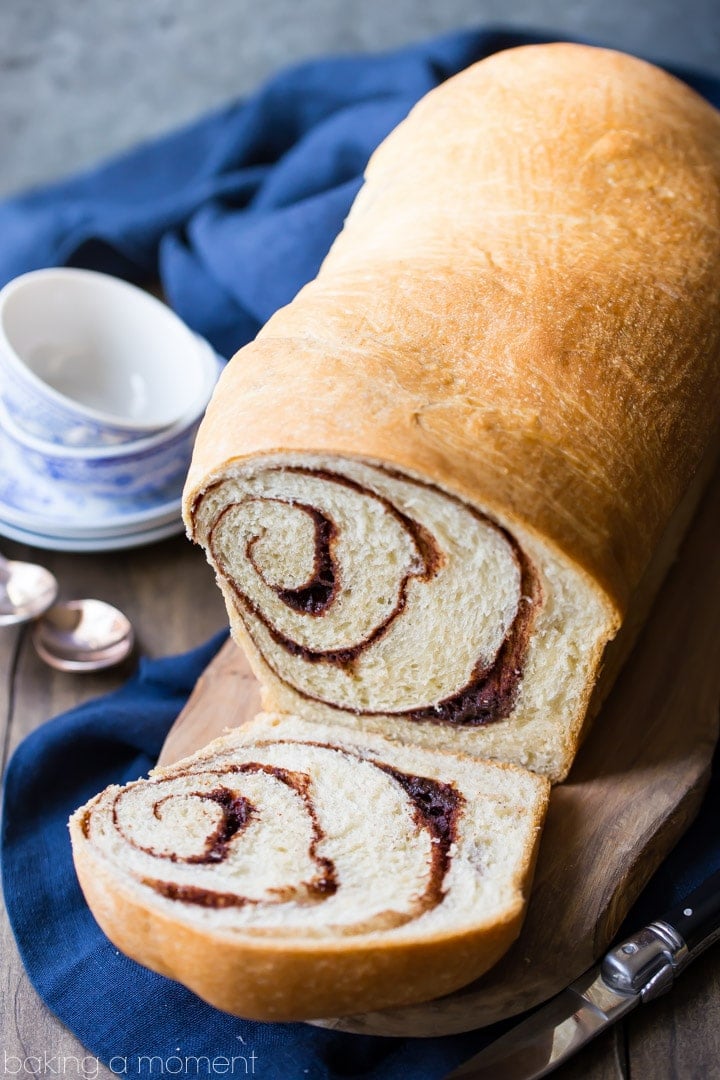 Cinnamon bread recipe, baked, cut, and displayed with blue and white teacups in the background.