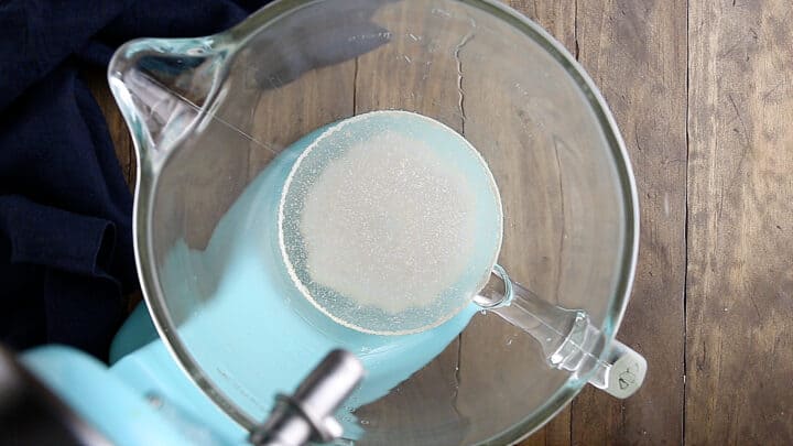 Foamy dissolved yeast in a large glass mixing bowl.