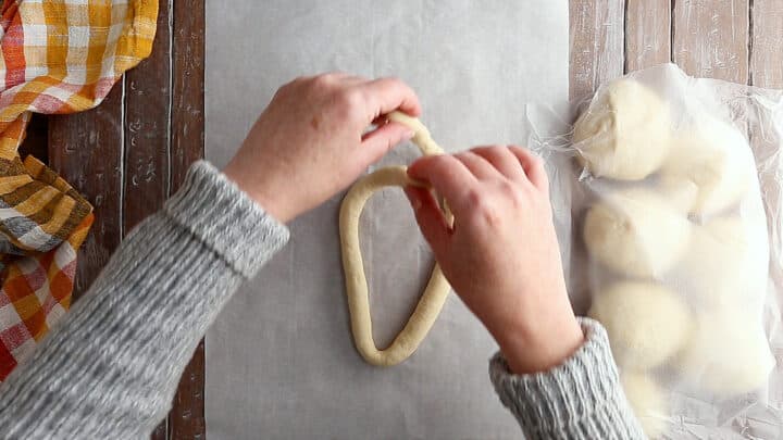 Pulling the ends of the soft pretzel dough down and towards the center.