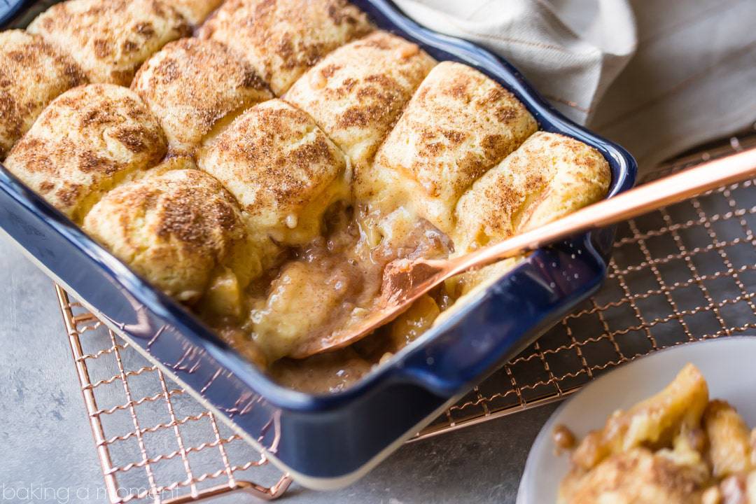 Snickerdoodle Apple Cobbler in a dark blue baking dish on a copper cooling rack. 