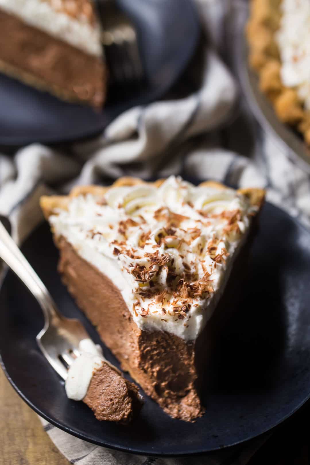 Thick slice of homemade chocolate cream pie with whipped cream and chocolate shavings.