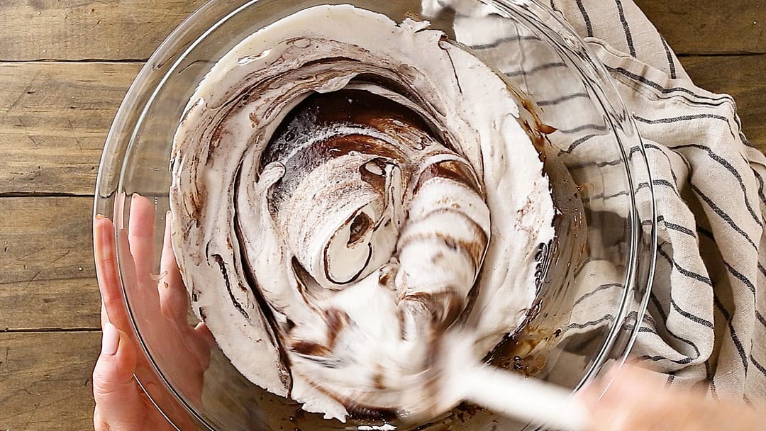 Folding melted chocolate into whipped cream.