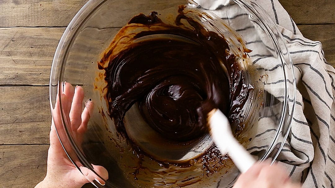 Stirring melted chocolate in a large mixing bowl.