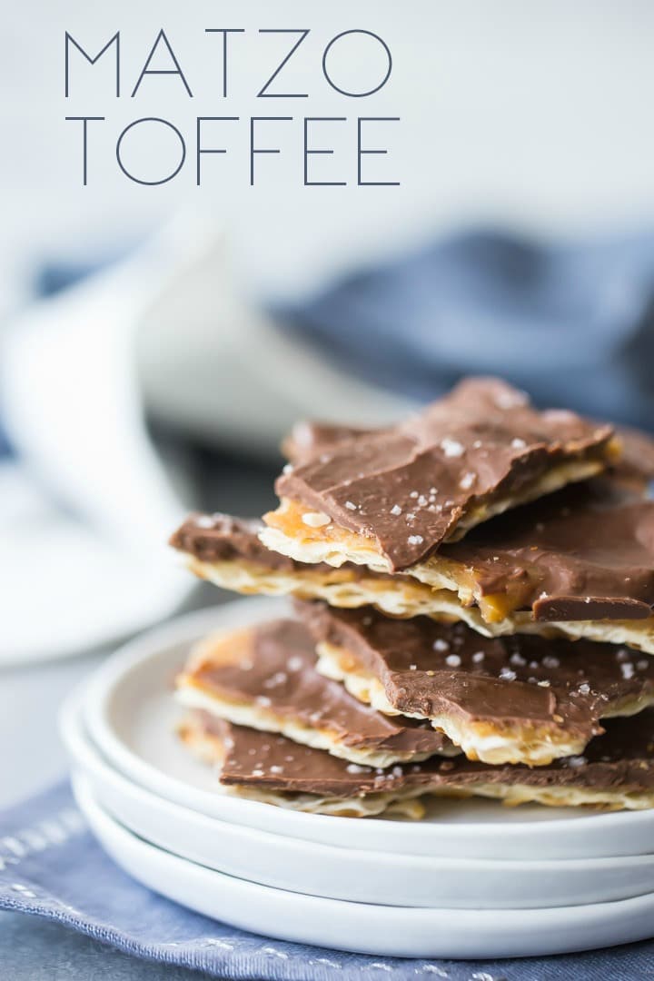 Small white plates on a blue napkin, piled with a stack of matzo toffee, with a text overlay.