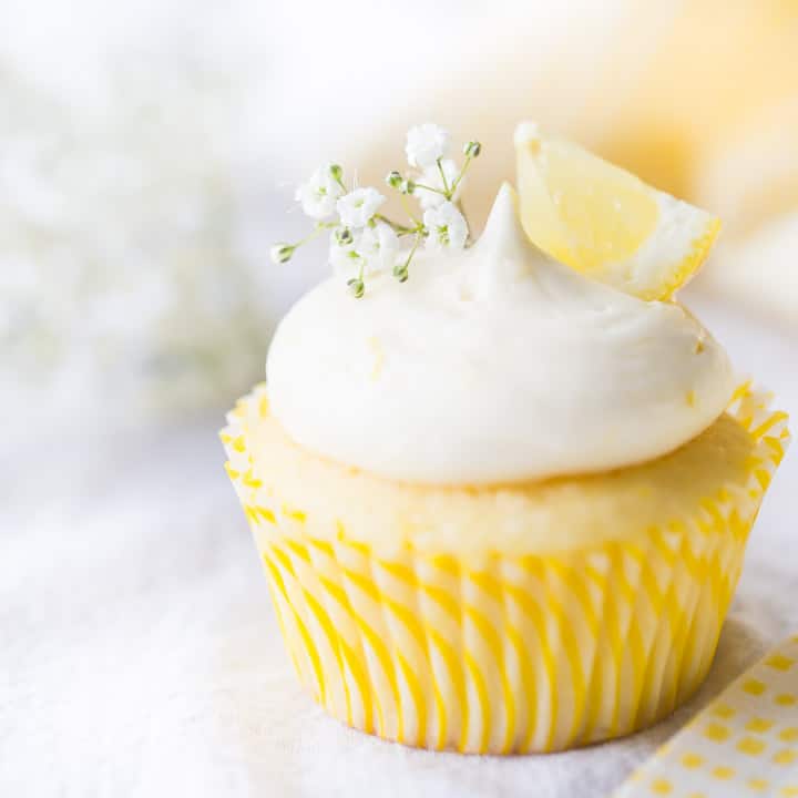 Lemon cupcake with lemon curd filling & lemon cream cheese frosting, garnished with baby's breath and a wedge of fresh lemon.