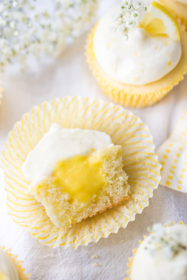 Overhead view of lemon cupcake cut in half, showing lemon curd filling and cream cheese frosting.