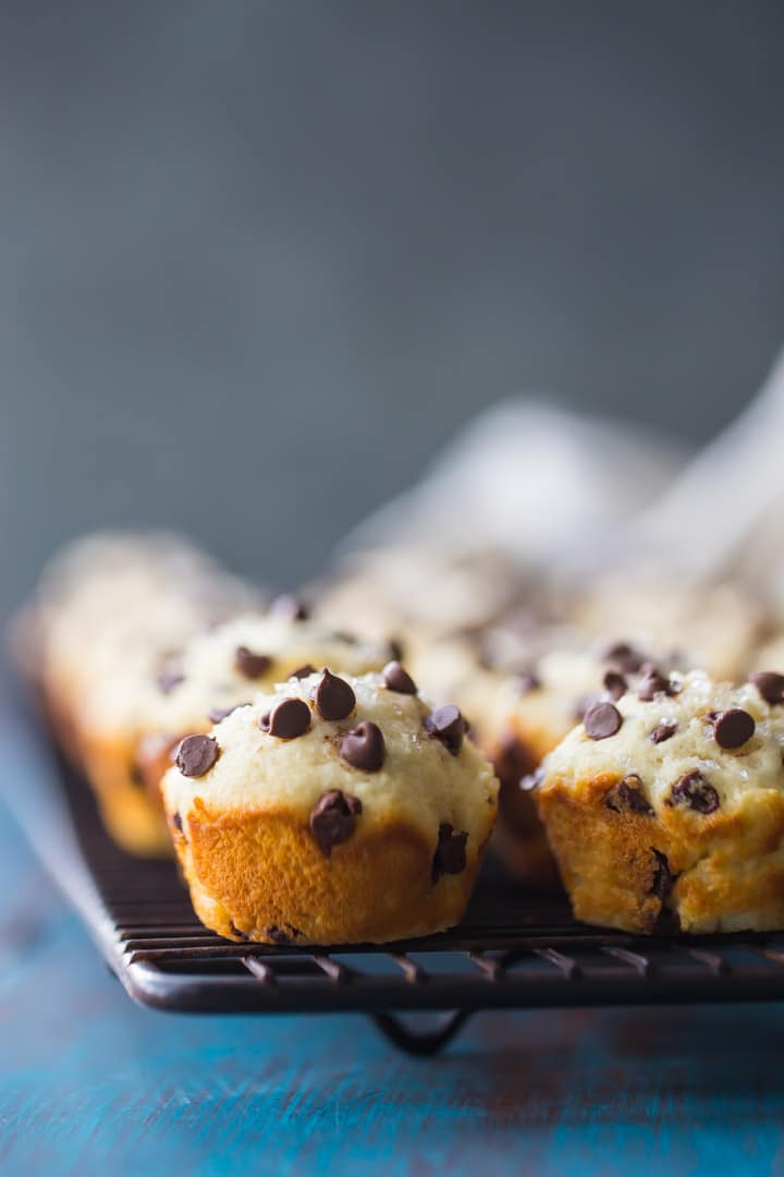 Vertical image of a batch of chocolate chip mini-muffins on a wire cooling rack.