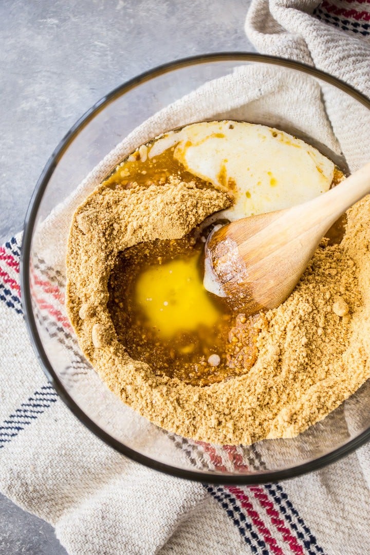 Overhead image of a bowl of graham cracker crumbs with melted butter poured in to make graham cracker crust.