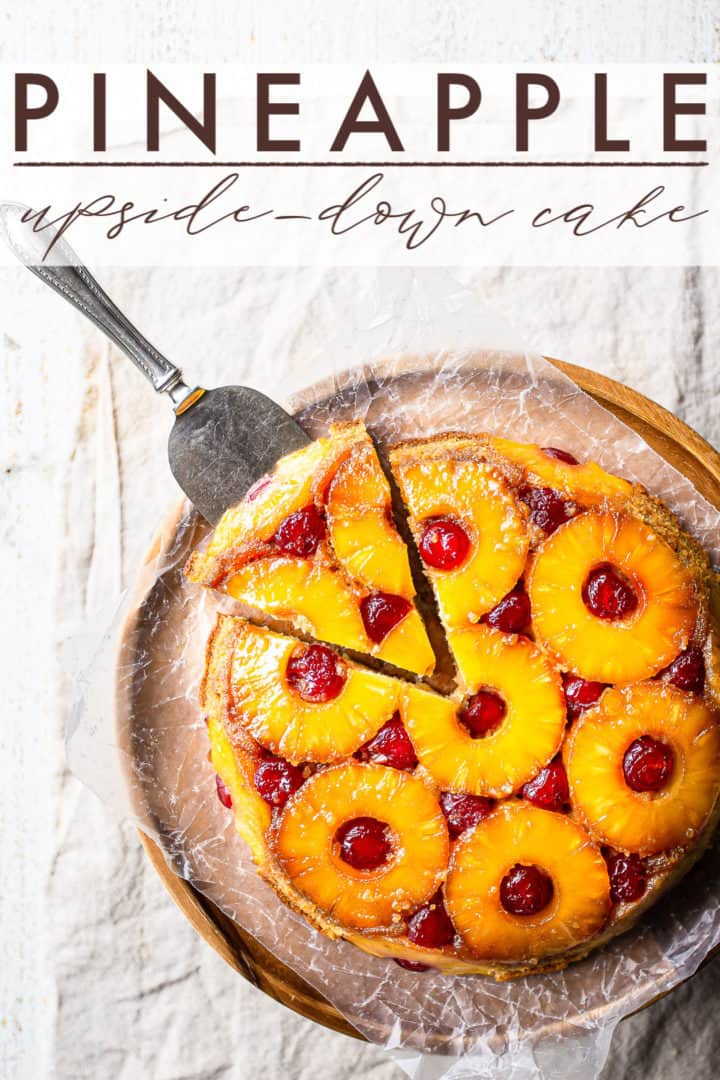 Pineapple upside-down cake baked in a round pan and served on a wooden pedestal.