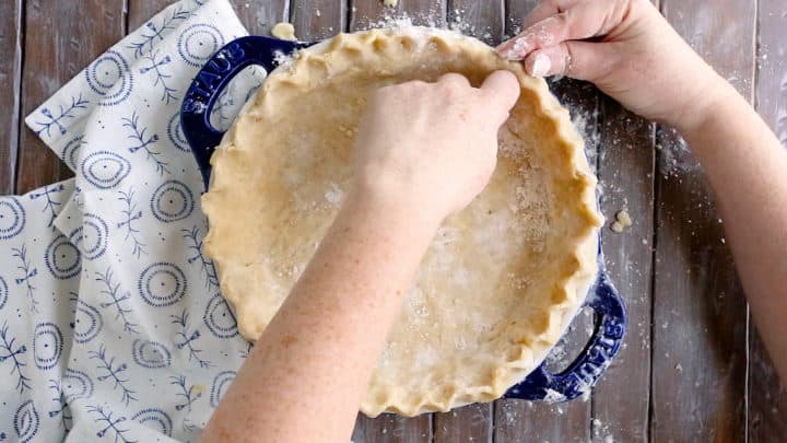 Crimping the edge of an unbaked pie crust.