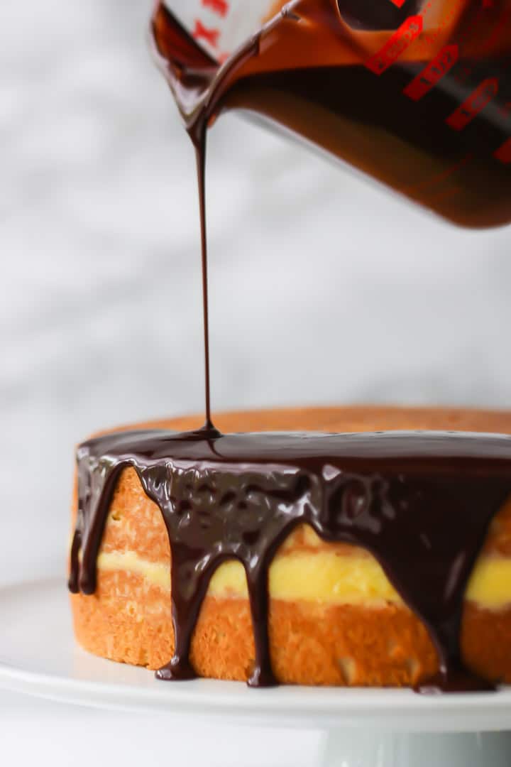 Drizzling shiny chocolate glaze over a cake with a drip edge.