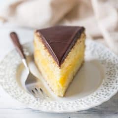 Slice of Boston Cream Pie with moist vanilla cake sandwiched around rich pastry cream filling, and a shiny chocolate glaze topping.