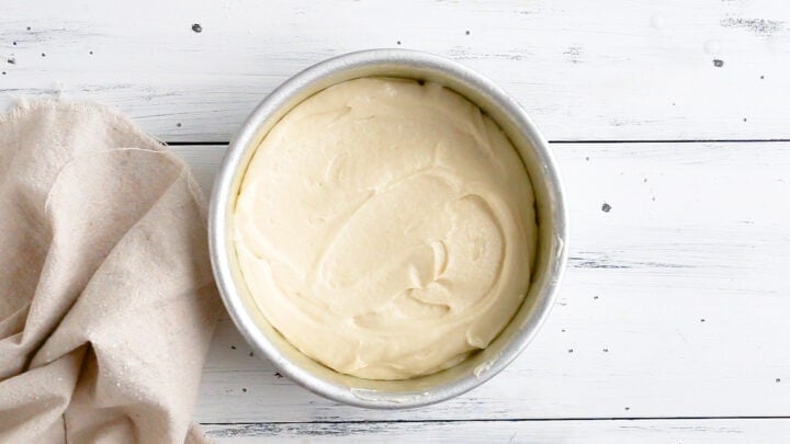 Unbaked vanilla cake batter in a greased, parchment-lined 6-inch round cake pan.