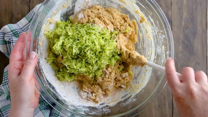 Adding shredded, drained zucchini to the batter.