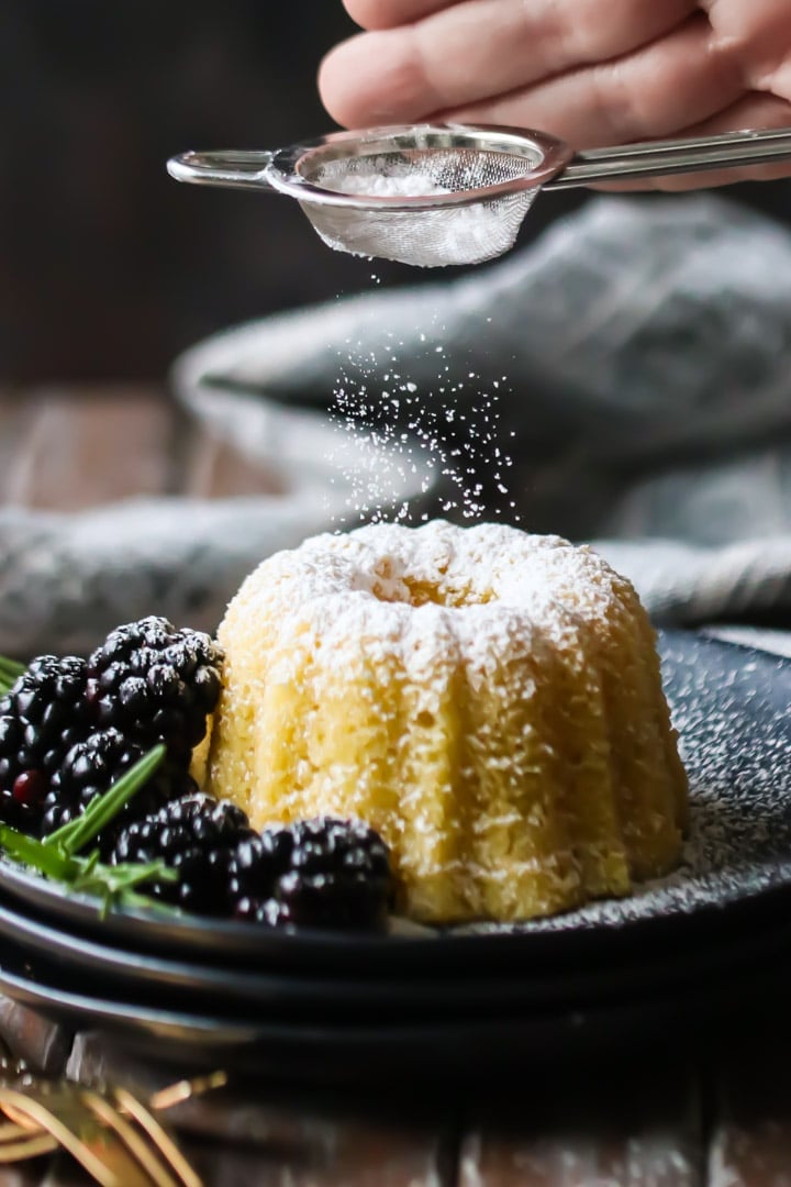  Dusting a simple olive oil cake recipe with powdered sugar from a small sieve.