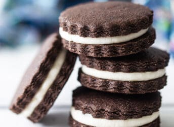 Homemade Oreos stacked on a white surface with a blue napkin in the background.
