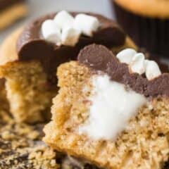 Close-up image of a s'mores cupcake, cut in half to show the marshmallow filling, with a text overlay above that reads "S'mores Cupcakes."