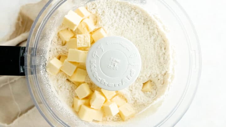 Adding butter to dry ingredients in a food processor.