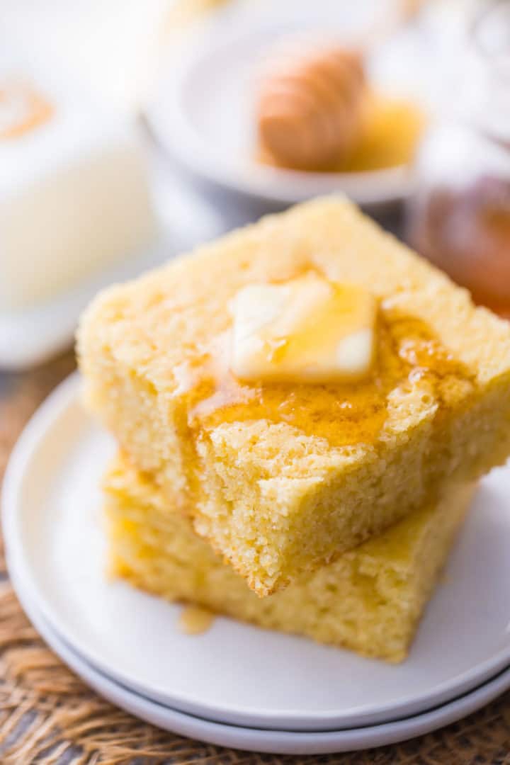 Easy cornbread recipe cut into squares and topped with butter and a drizzle of honey.
