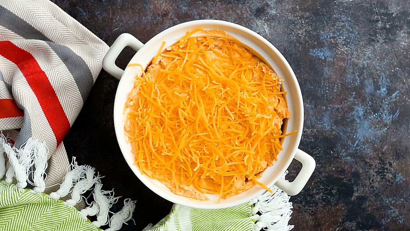 Buffalo chicken dip in a baking dish with shredded cheese on top.