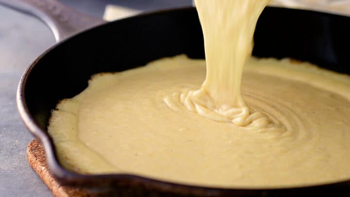 Pouring cornbread batter into a hot buttered skillet.