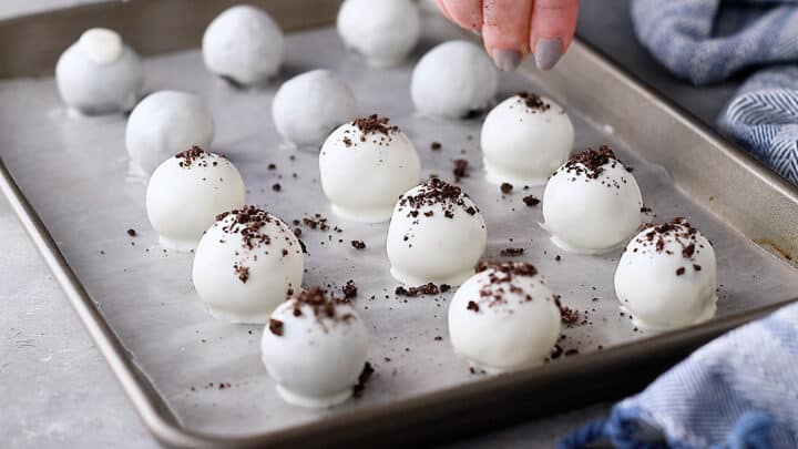 Sprinking Oreo balls with cookie crumbs.